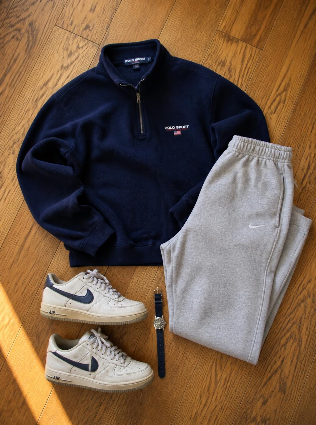 Navy quarter-zip fleece with grey joggers, trainers and a watch