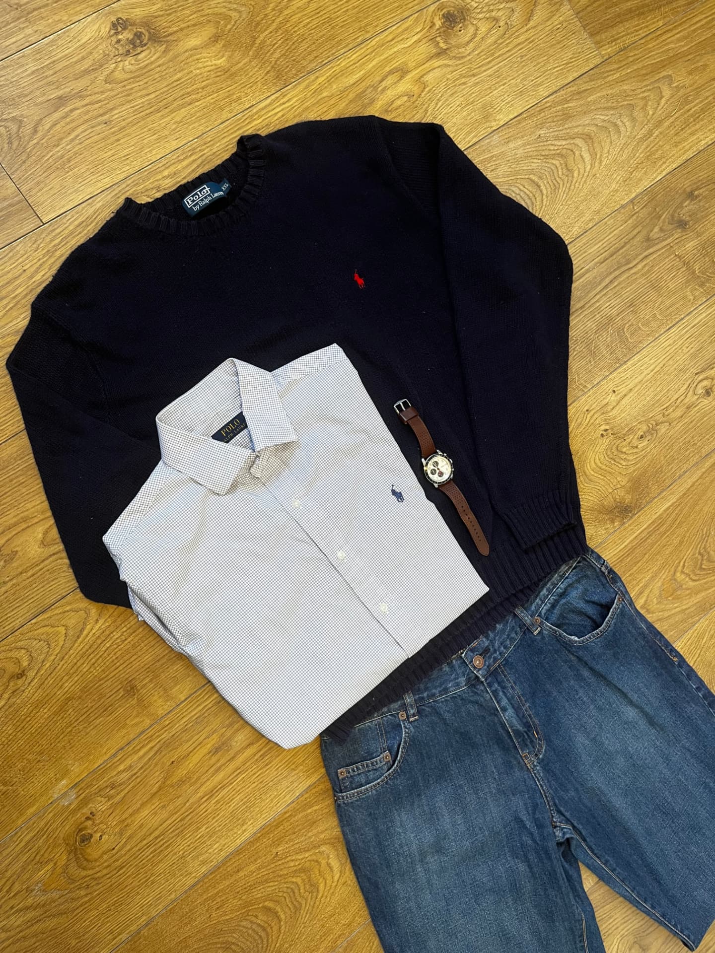 Navy Ralph Lauren knit, checked Polo shirt, watch and denim laid out on oak flooring